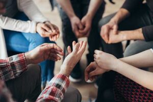 people sit in a circle with all of their hands in their laps while discussing the importance of substance abuse treatment programs