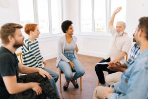 a person raises their hand in a group therapy session during their fentanyl addiction treatment program
