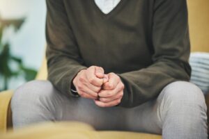 a person holds their hands together while sitting in their opioid addiction treatment program