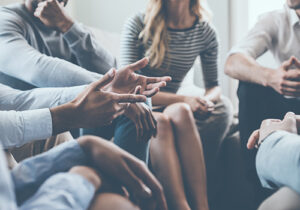 a group of people sit around together in their group therapy program discussing current events and feelings