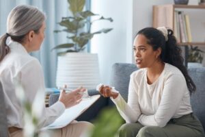woman sits and listens to her therapist in her psychotherapy program