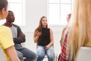 a woman talks in group therapy about the differences of opioid vs opiate